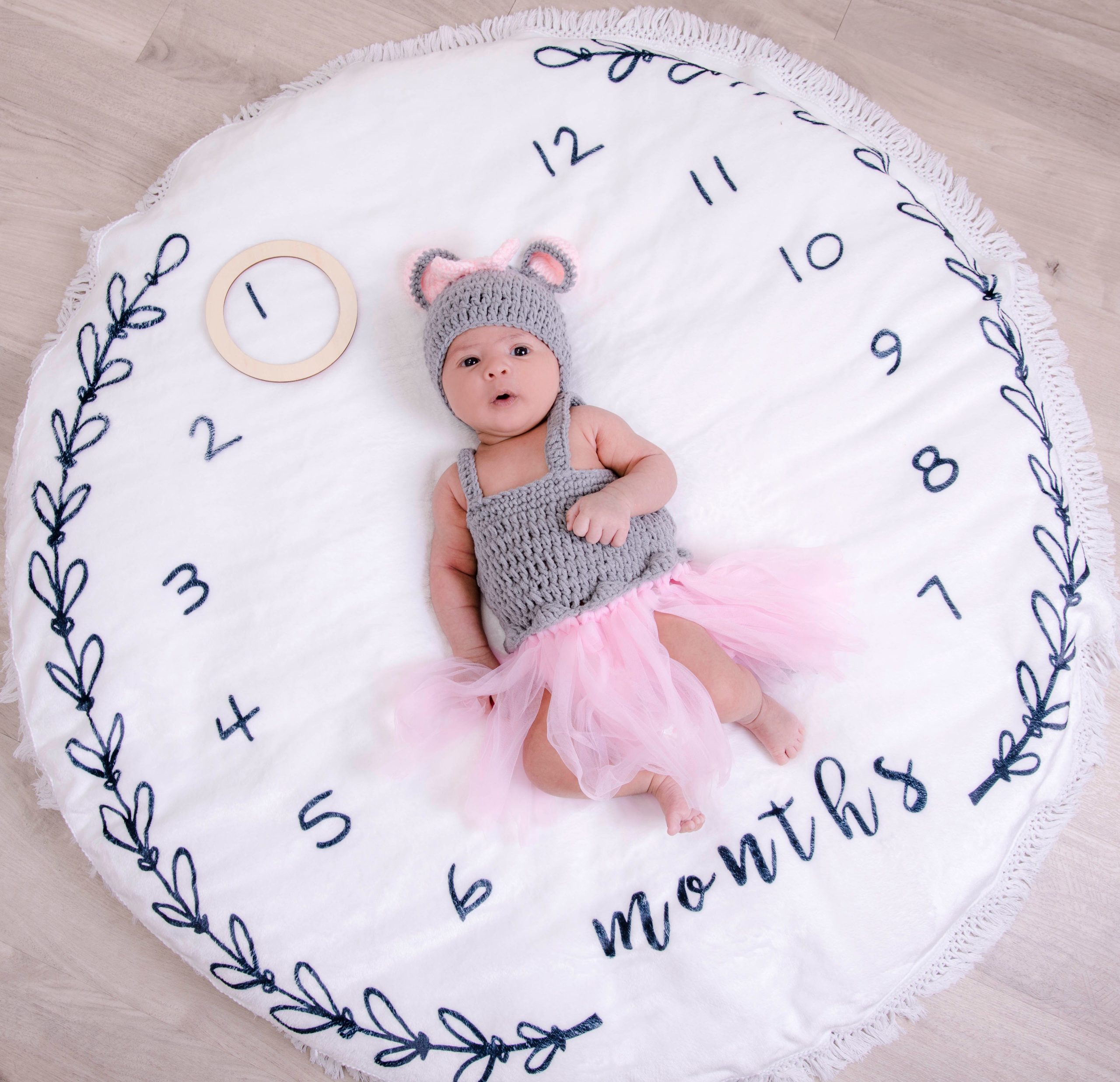 Baby photographed on a milestone blanket with a month marker, illustrating monthly growth tracking.